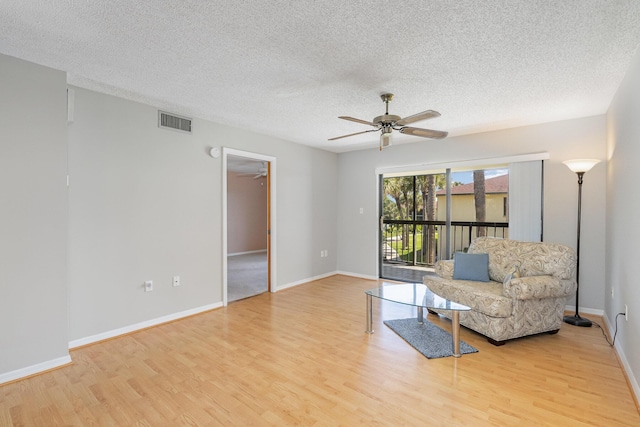 living area with a ceiling fan, baseboards, visible vents, and light wood finished floors