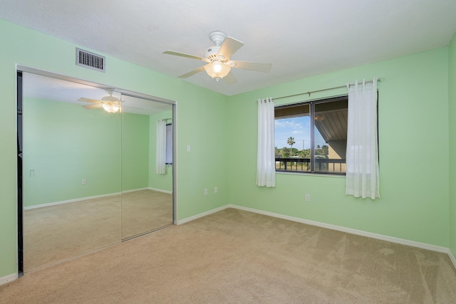 unfurnished bedroom featuring light carpet, visible vents, baseboards, a ceiling fan, and a closet