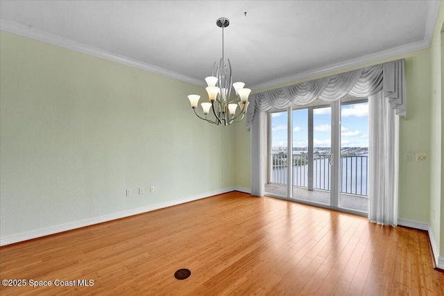 spare room with light wood-style flooring, a water view, baseboards, ornamental molding, and an inviting chandelier