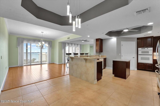 kitchen with white double oven, open floor plan, a center island, light countertops, and pendant lighting