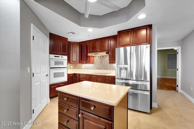 kitchen with stainless steel fridge with ice dispenser, a center island, black electric stovetop, under cabinet range hood, and double oven