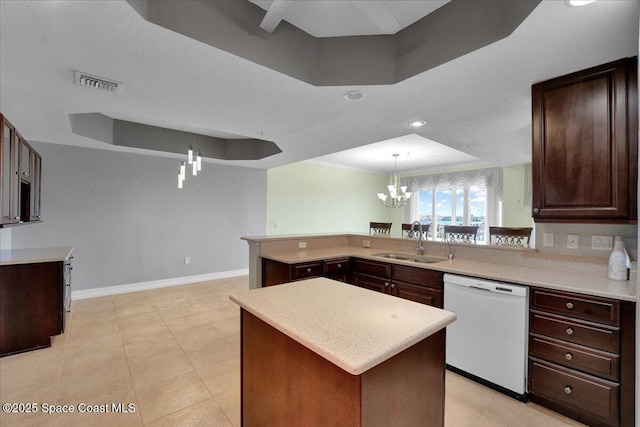 kitchen with a kitchen island, a raised ceiling, light countertops, and white dishwasher