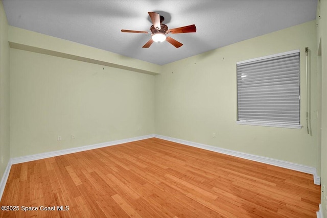 spare room with baseboards, ceiling fan, and light wood-style floors