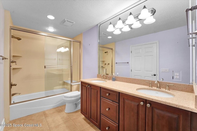 bathroom with bath / shower combo with glass door, a sink, visible vents, and tile patterned floors
