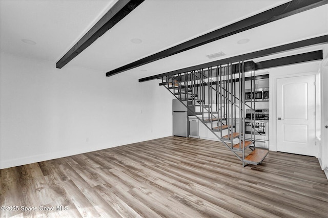 unfurnished living room with visible vents, beamed ceiling, stairway, and wood finished floors