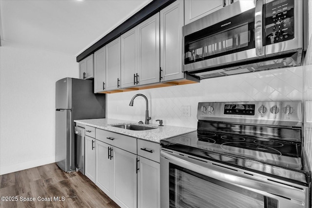 kitchen featuring tasteful backsplash, dark wood finished floors, gray cabinets, stainless steel appliances, and a sink