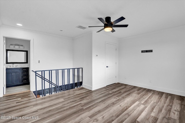 unfurnished room featuring light wood finished floors, ornamental molding, visible vents, and baseboards