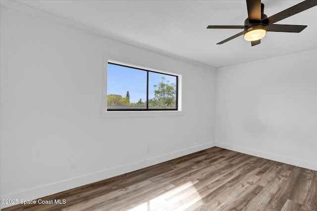 spare room with a ceiling fan, crown molding, baseboards, and wood finished floors