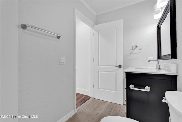 half bath featuring ornamental molding, vanity, baseboards, and wood finished floors