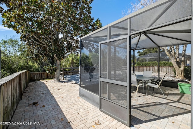 view of patio with glass enclosure and fence