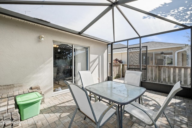 view of patio with outdoor dining area and glass enclosure