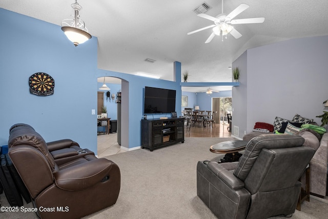 living area featuring arched walkways, carpet, lofted ceiling, visible vents, and ceiling fan