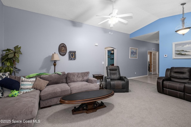 living area featuring ceiling fan, arched walkways, baseboards, vaulted ceiling, and carpet