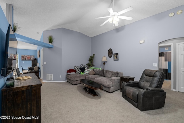 carpeted living area featuring baseboards, visible vents, a ceiling fan, arched walkways, and vaulted ceiling