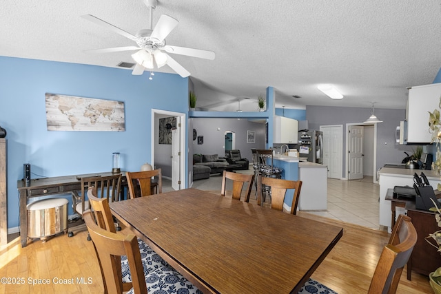 dining space with vaulted ceiling, light wood-style flooring, and visible vents