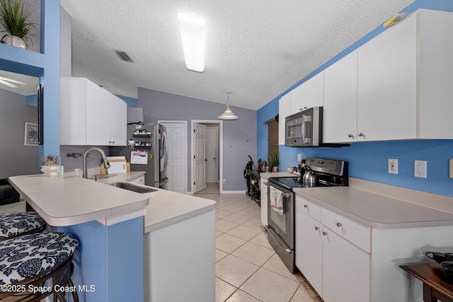 kitchen featuring light tile patterned floors, stainless steel appliances, lofted ceiling, light countertops, and a peninsula