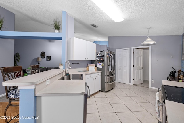 kitchen with stainless steel appliances, lofted ceiling, light countertops, white cabinetry, and a sink