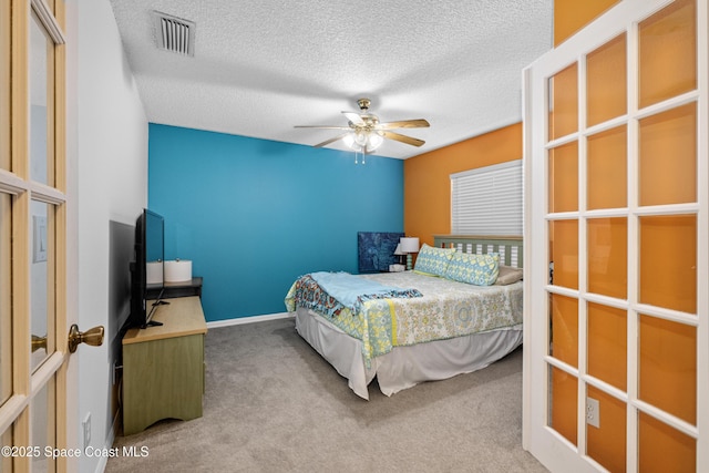 bedroom with carpet floors, visible vents, a textured ceiling, and a ceiling fan