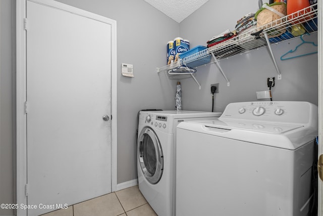 laundry area featuring laundry area, washing machine and dryer, light tile patterned floors, and a textured ceiling