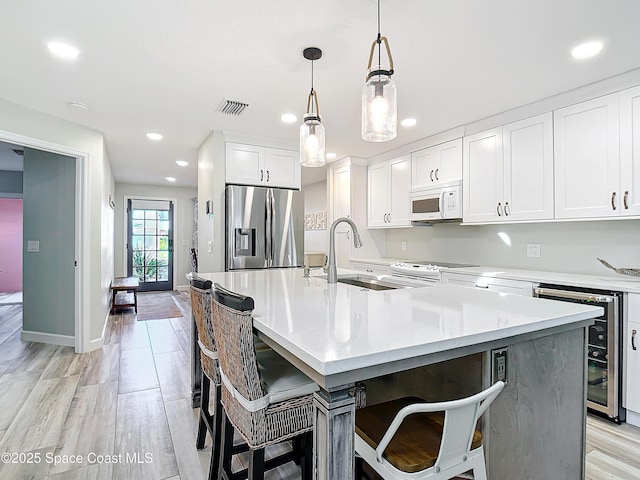 kitchen featuring visible vents, white microwave, white cabinetry, beverage cooler, and stainless steel fridge with ice dispenser