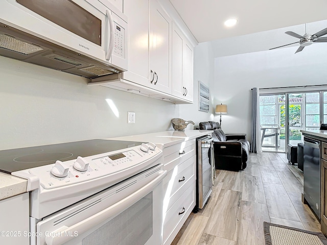 kitchen featuring beverage cooler, white appliances, white cabinetry, a ceiling fan, and light wood-type flooring