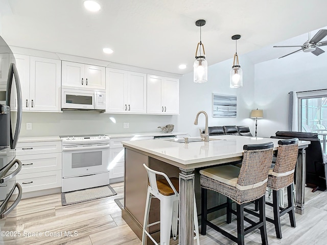 kitchen with light wood-style floors, white appliances, light countertops, and a sink