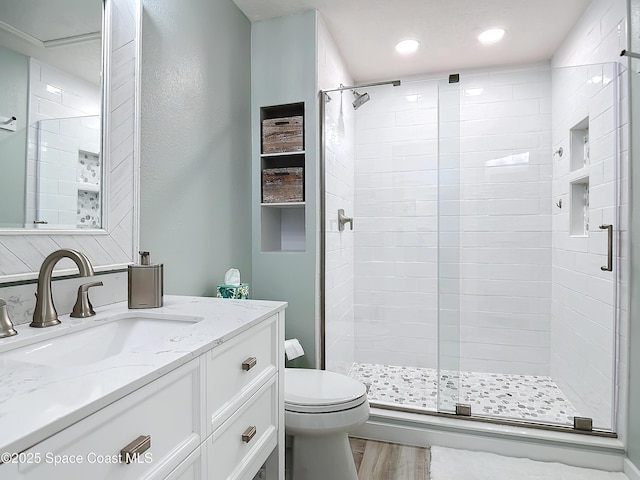 full bath featuring toilet, wood finished floors, vanity, a shower stall, and recessed lighting