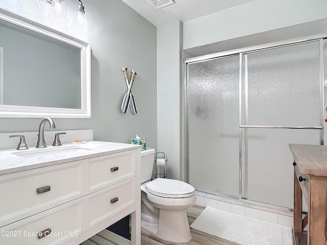 full bath with toilet, a stall shower, wood finished floors, and vanity