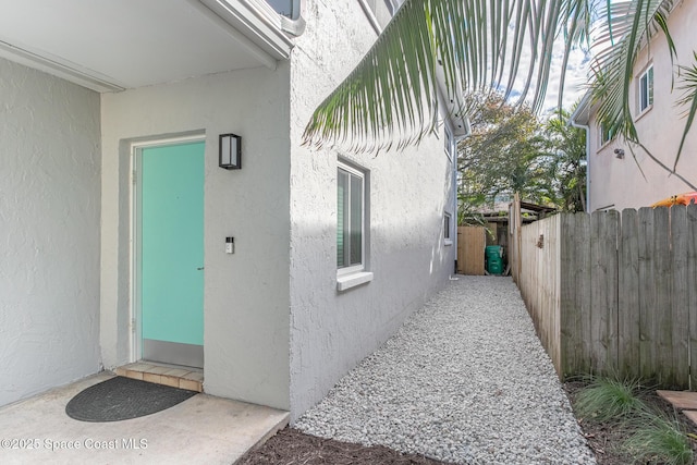 property entrance with fence and stucco siding