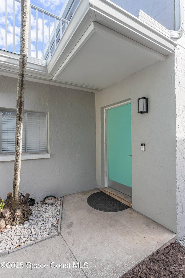 view of exterior entry with a patio and stucco siding