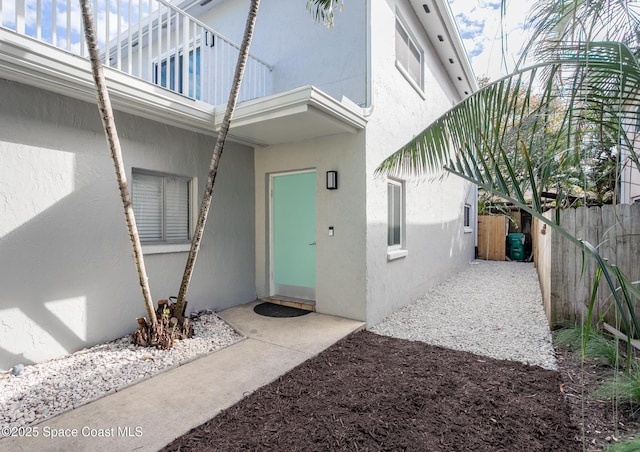 view of exterior entry featuring fence and stucco siding