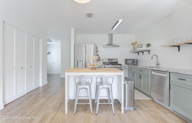 kitchen featuring open shelves, stainless steel appliances, visible vents, a sink, and wall chimney range hood