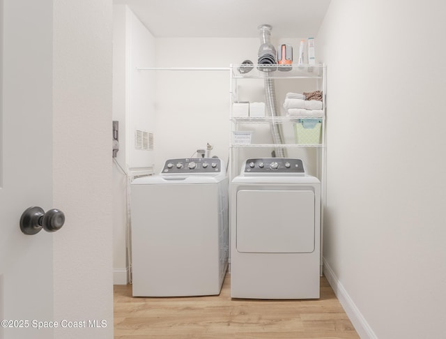 washroom featuring visible vents, light wood-style flooring, separate washer and dryer, laundry area, and baseboards