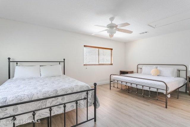 bedroom with light wood-style flooring, visible vents, ceiling fan, and baseboards