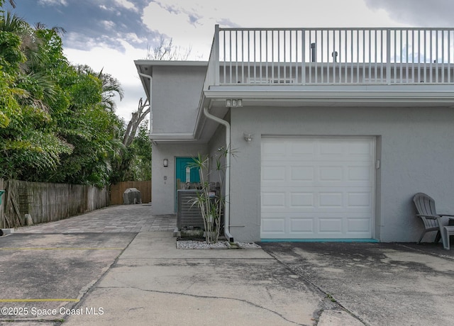 exterior space with a garage, fence, a balcony, and stucco siding