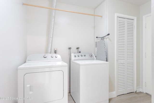 clothes washing area featuring laundry area, light wood-style flooring, and washer and dryer