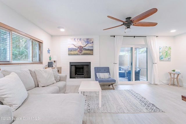 living room with recessed lighting, a fireplace, and light wood-style floors