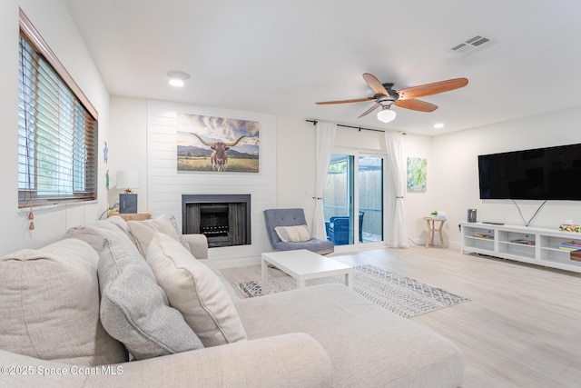 living area with recessed lighting, visible vents, light wood-style floors, a ceiling fan, and a large fireplace