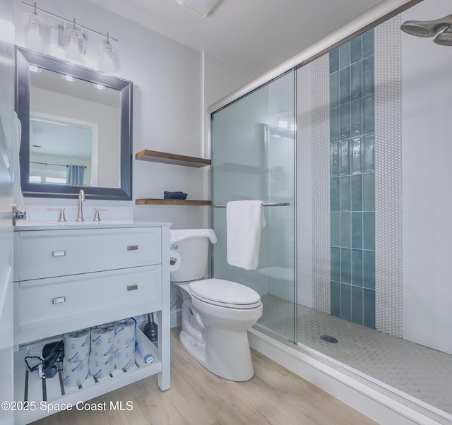 full bathroom featuring toilet, a shower stall, wood finished floors, and vanity