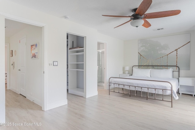 bedroom featuring ceiling fan, light wood-style flooring, visible vents, baseboards, and a spacious closet