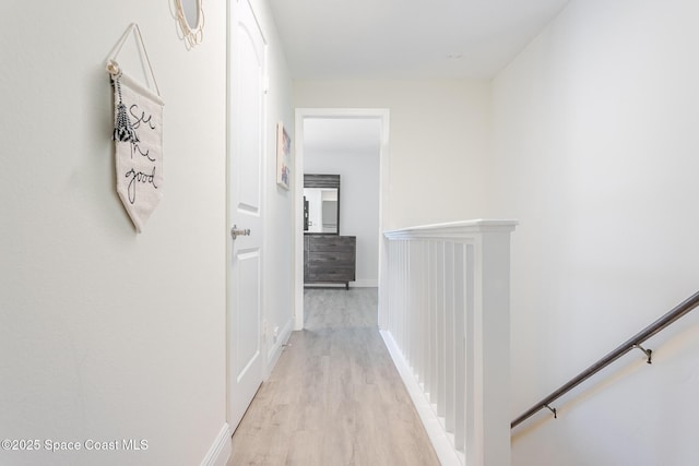 hall with baseboards, an upstairs landing, and light wood-style floors