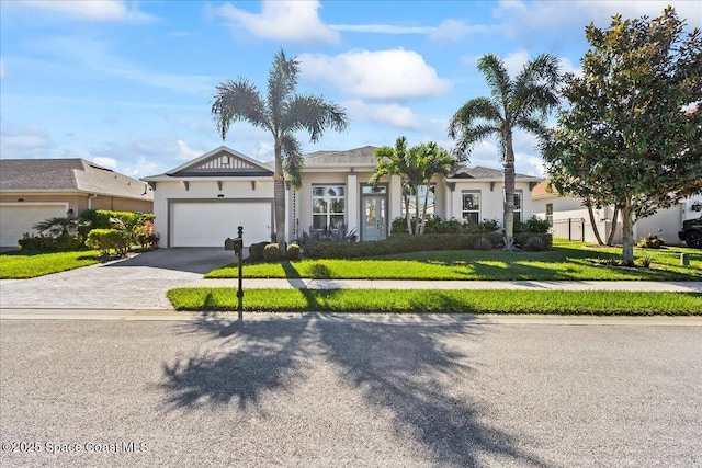 view of front of property featuring a garage, a front lawn, decorative driveway, and stucco siding