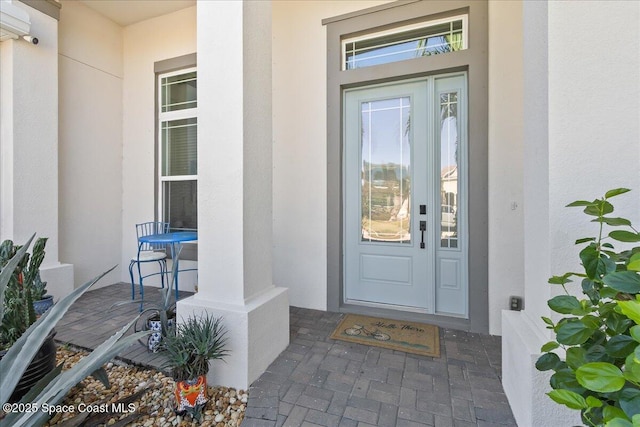 entrance to property with a porch and stucco siding