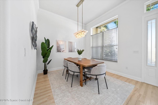 dining space featuring a notable chandelier, ornamental molding, light wood-type flooring, and baseboards