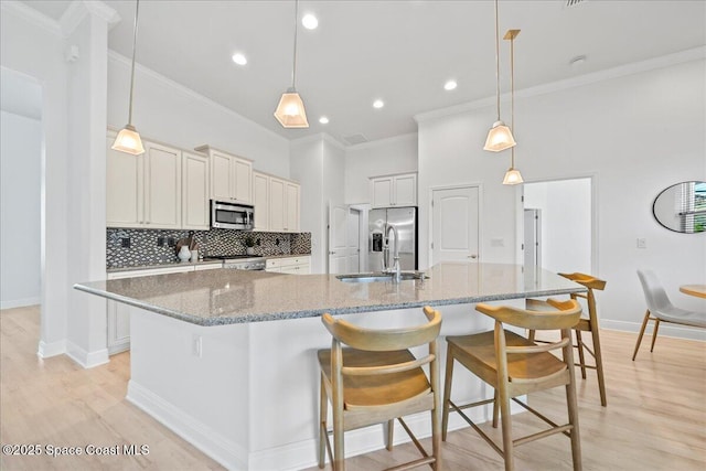 kitchen featuring appliances with stainless steel finishes, backsplash, a sink, and light wood-style flooring