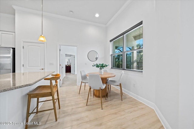 dining room featuring crown molding, recessed lighting, a high ceiling, light wood-type flooring, and baseboards