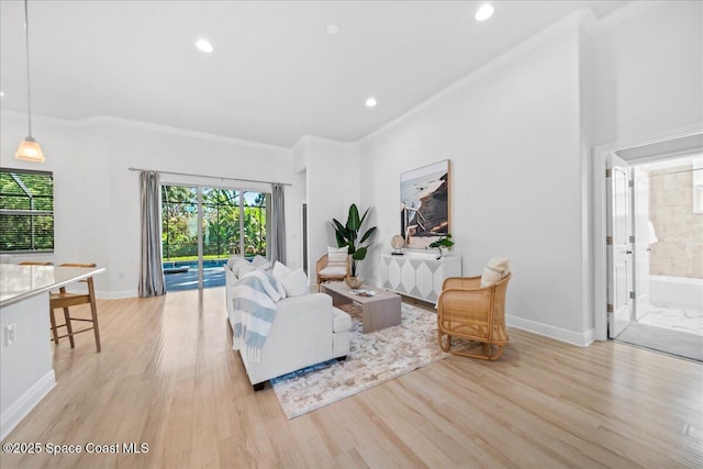 living area featuring light wood-style floors, crown molding, and baseboards