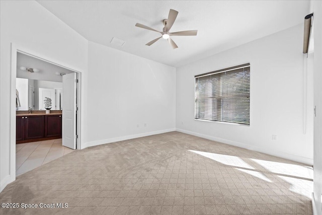 unfurnished bedroom featuring a ceiling fan, connected bathroom, baseboards, and a sink