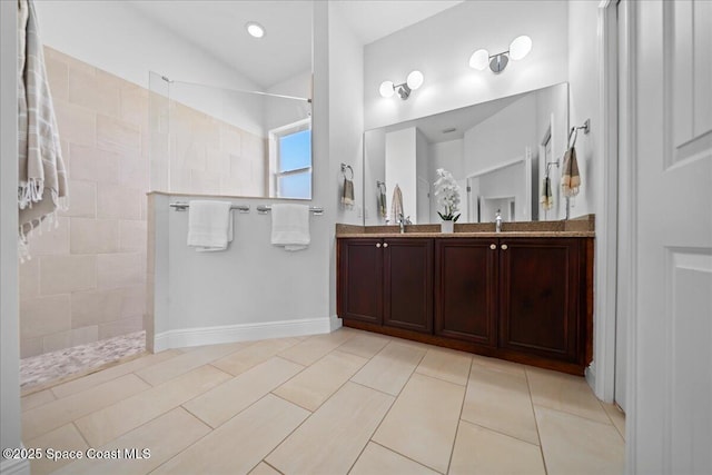 bathroom with double vanity, lofted ceiling, a sink, walk in shower, and tile patterned floors