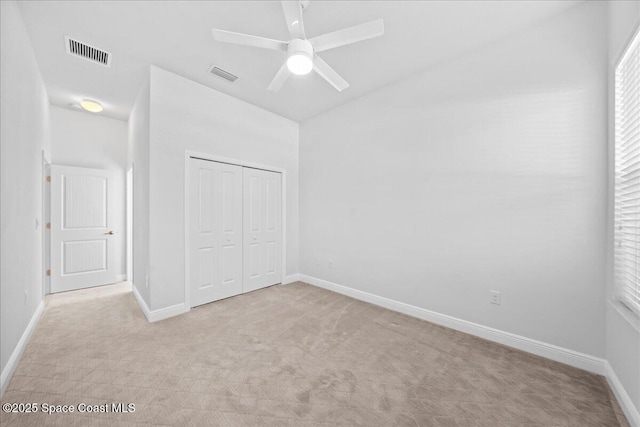 unfurnished bedroom with light carpet, a closet, visible vents, and baseboards